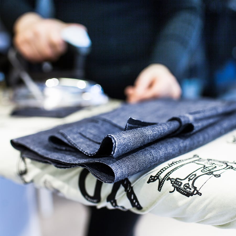 cropped image of woman ironing fabric in jeans fac CCSTHE4a